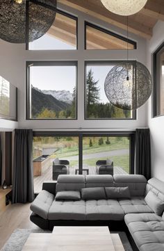 a modern living room with large windows and grey couches in front of the sliding glass doors