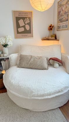 a large round bed in the corner of a room next to a lamp and pictures on the wall