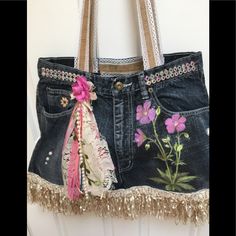 a purse hanging on the side of a door with flowers painted on it and tassels