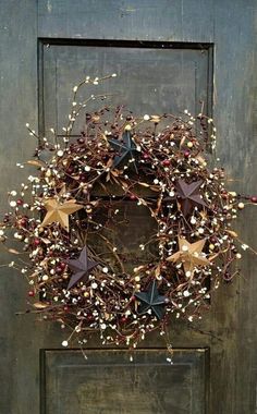 a wreath is hanging on a door with red berries and starbursts in it