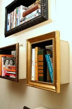 two framed bookshelves are on the wall above a sink and mirror with gold trim