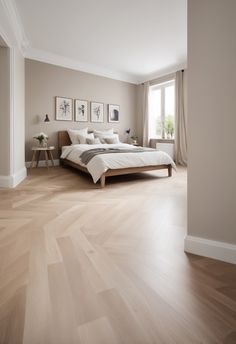 a large bedroom with hardwood floors and white walls is pictured in this image, there are pictures on the wall above the bed