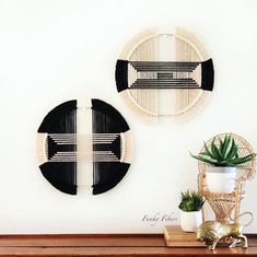 two black and white wall hangings next to a potted plant on a table