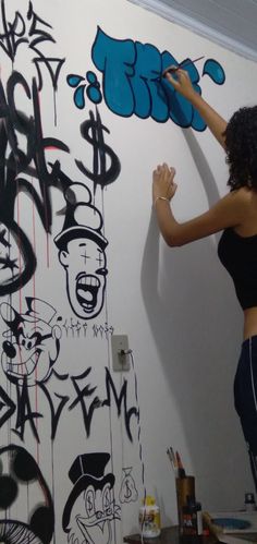 a woman is painting graffiti on the wall