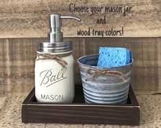 a mason jar and soap dispenser are sitting on a tray with a blue sponge in it