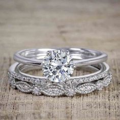 two wedding rings with diamonds on top of each other, one in white gold and the other in silver