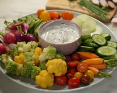 a white plate topped with lots of veggies and dip