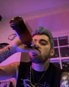 a man drinking from a bottle while wearing a black shirt