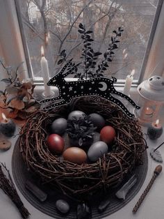 a bird's nest with eggs and candles in front of a window