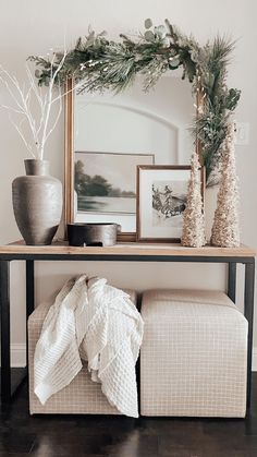 a table with a mirror, vase and pictures on it