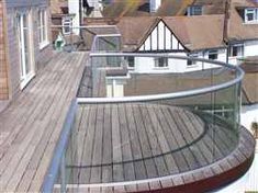 a wooden deck with glass railings and houses in the background