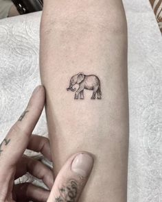 a small elephant tattoo on the left inner forearm and arm, with an inked outline