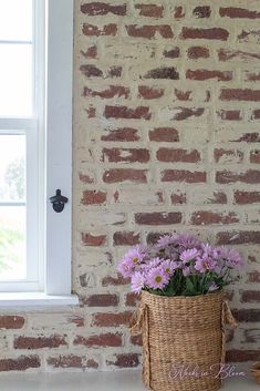 a basket full of flowers sitting on top of a counter next to a brick wall