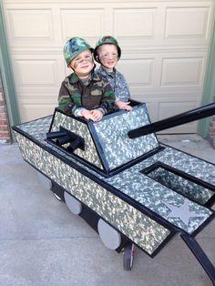 two young boys sitting on top of a cart made to look like a boat with wheels