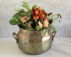 a potted plant with orange and pink flowers in it on a white table top