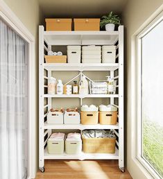 a white shelving unit filled with lots of boxes and containers next to a window