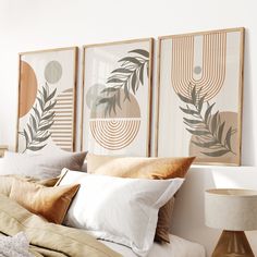 a bed with pillows and blankets on top of it next to two framed art pieces