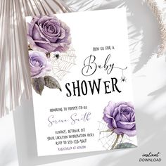 a baby shower card with purple roses and spider webs on the bottom, in front of palm leaves