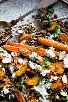 a plate with carrots, lentils and feta cheese on it next to two spoons