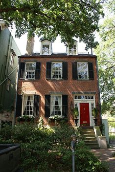 a brick house with black shutters and red door