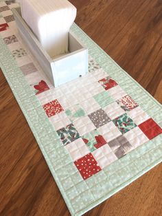 the table runner is made with patchwork fabric and has a white box on it