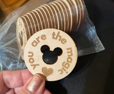 a hand holding a wooden button with the words are the magic on it