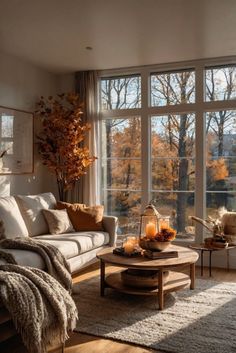 a living room filled with lots of furniture next to large windows covered in fall foliage