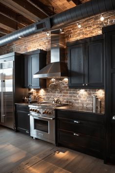 a kitchen with black cabinets and stainless steel appliances in the middle of an open floor plan