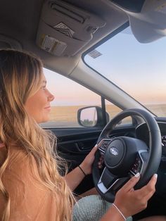 a woman sitting in the driver's seat of a car looking out at the ocean