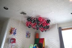 two children playing in a play room with spider webs hanging from the ceiling and toys on the floor