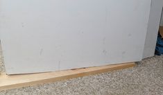 a white refrigerator sitting on top of a wooden floor next to a blue pair of shoes