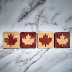 three wooden coasters with maple leaves on them sitting on a marble countertop in front of a marble background