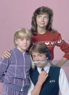 two women and a man pose for a portrait in front of a pink background stock photo