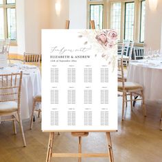 a wedding seating chart on a easel in a room with white tablecloths and chairs