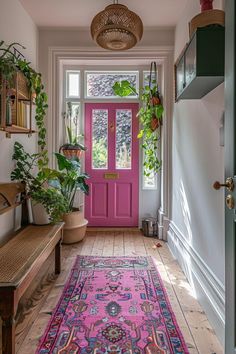 a bright pink door is in the hallway with potted plants on either side and a bench next to it