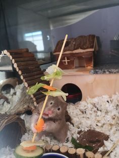 a hamster is sitting in the middle of some fake food and eating carrots