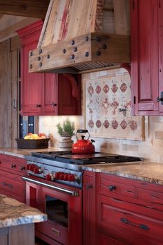 a red stove top oven sitting inside of a kitchen next to wooden cabinets and counter tops