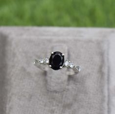 a black and white diamond ring sitting on top of a piece of cloth with grass in the background