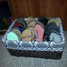 a basket filled with flip flops and slippers on top of carpeted floor