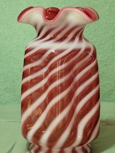 a red and white glass vase sitting on top of a table