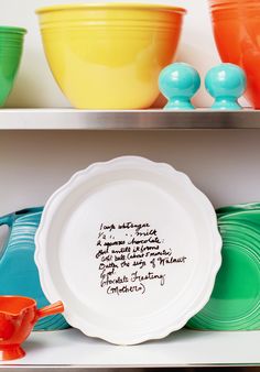 plates and bowls with writing on them are sitting on the shelf in front of each other