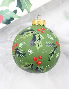 a green ornament with red berries and leaves on it