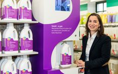 a woman standing in front of a shelf with cleaning products on it and she is smiling at the camera