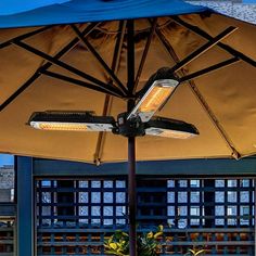 an umbrella that is on top of a table with some plants in it and the lights are on