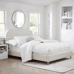 a white bed sitting in a bedroom on top of a hard wood floor