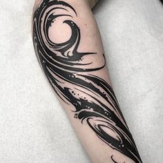 a woman's leg with black ink on it and an artistic wave tattoo design