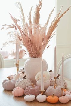 a white vase filled with lots of pink flowers next to candles and other decorative items