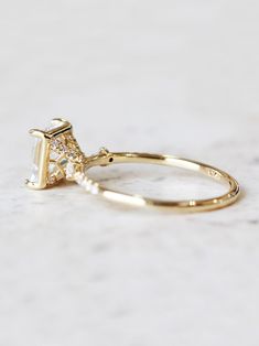 a yellow gold ring with a diamond in the middle and a small white diamond on top