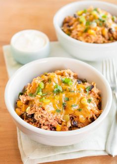 slow cooker chicken burrito bowls in white bowls on a wooden table with utensils