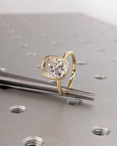 a diamond ring sitting on top of a piece of metal next to some screwdrivers